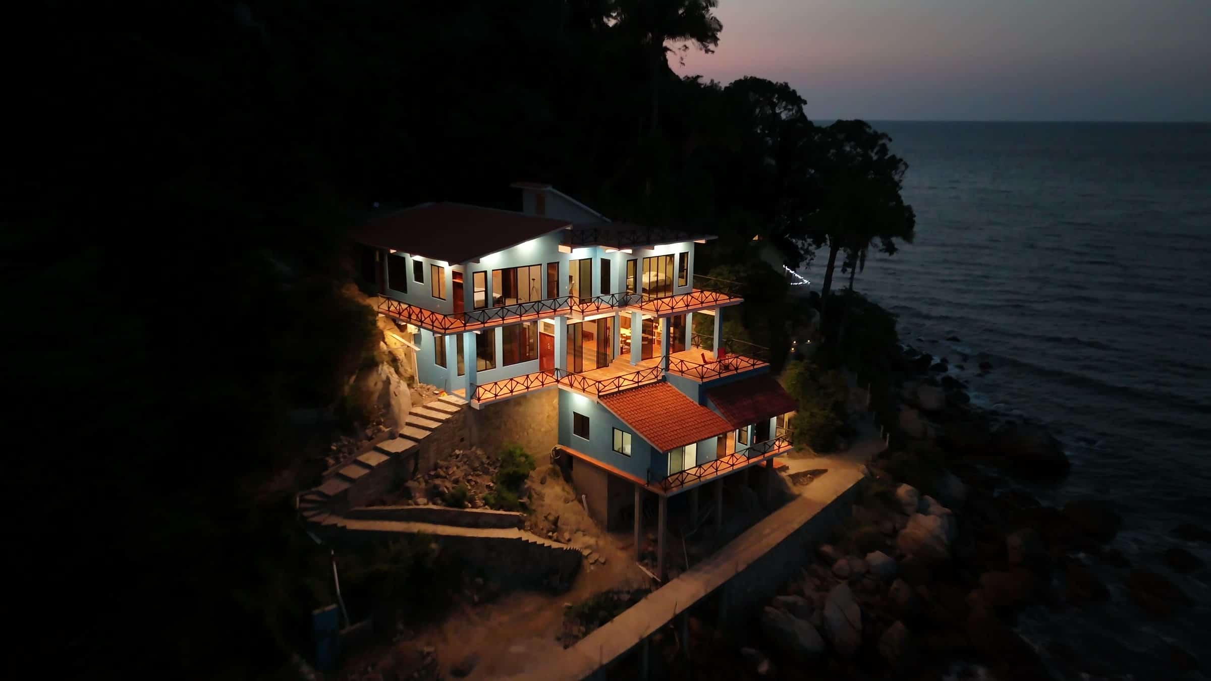 The house lit up at dusk, from the air